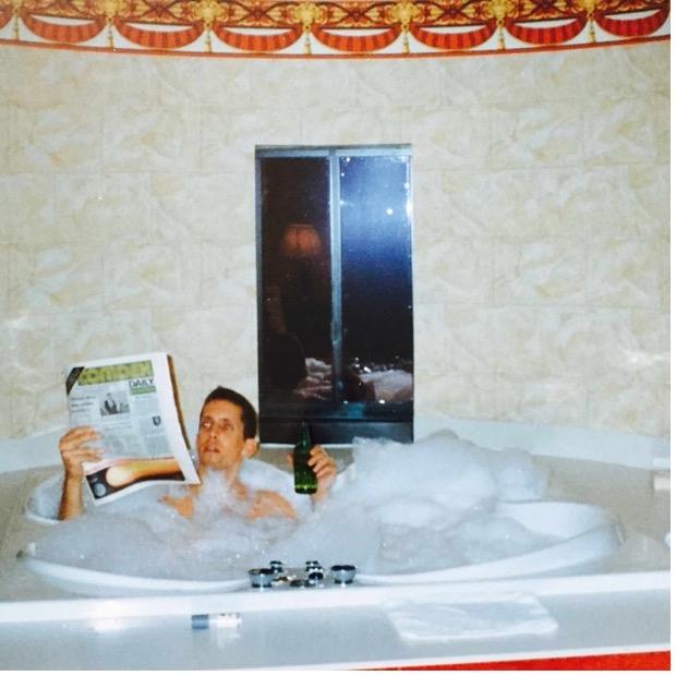 The writer, Steve Saunders, in a medieval-themed hot tub in 1991, with bubble bath, beer and holding a newspaper